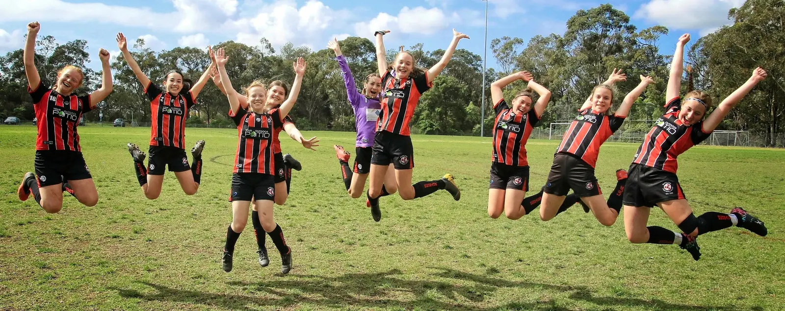 Blaxland Redbacks players jumping together on the football pitch